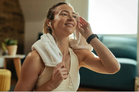 Mulher feliz com toalha, ouvindo música, descansando após o treino, destacando o tempo para a creatina fazer efeito.