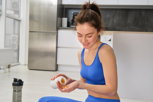 Jovem tomando probióticos para emagrecimento em casa, com garrafa de água ao lado.