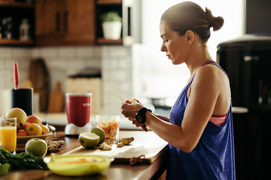 Mulher preparando ingredientes saudáveis na cozinha para probióticos para inchaço abdominal.